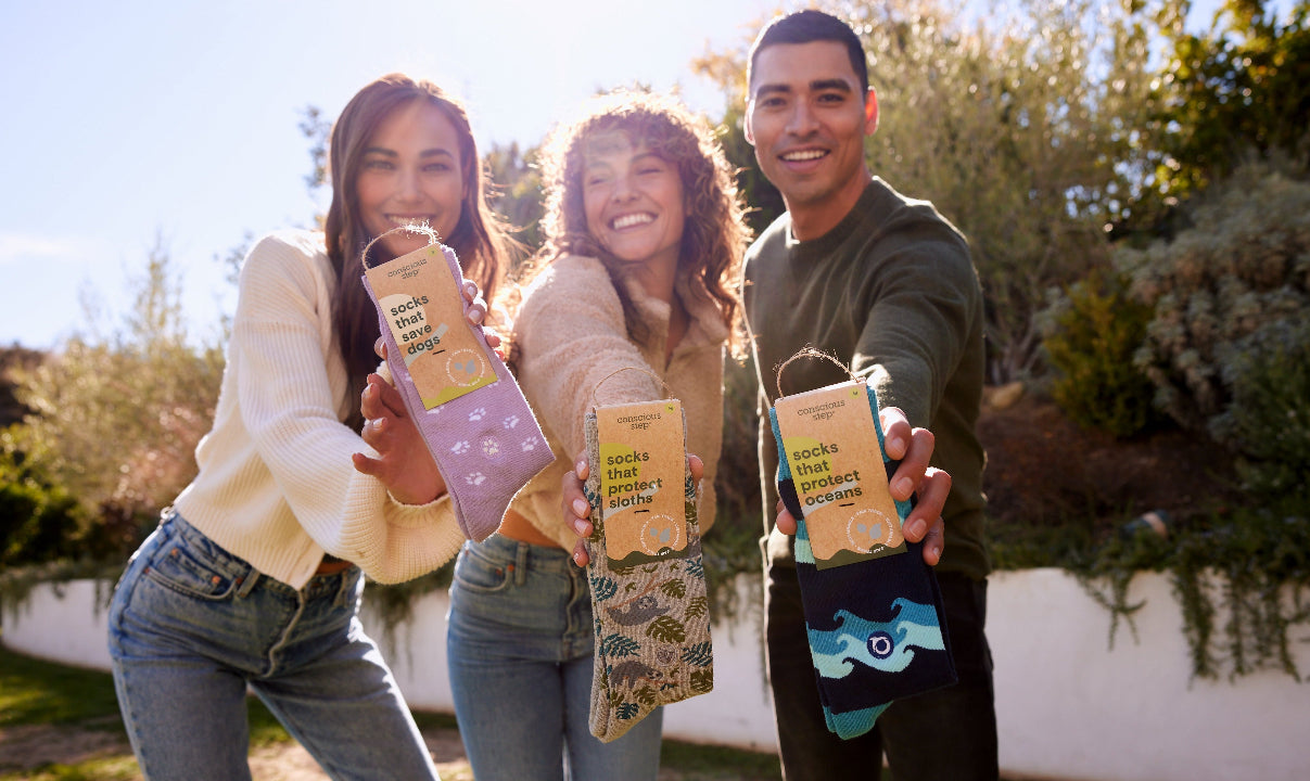 Three people holding colorful socks outdoors with a natural background